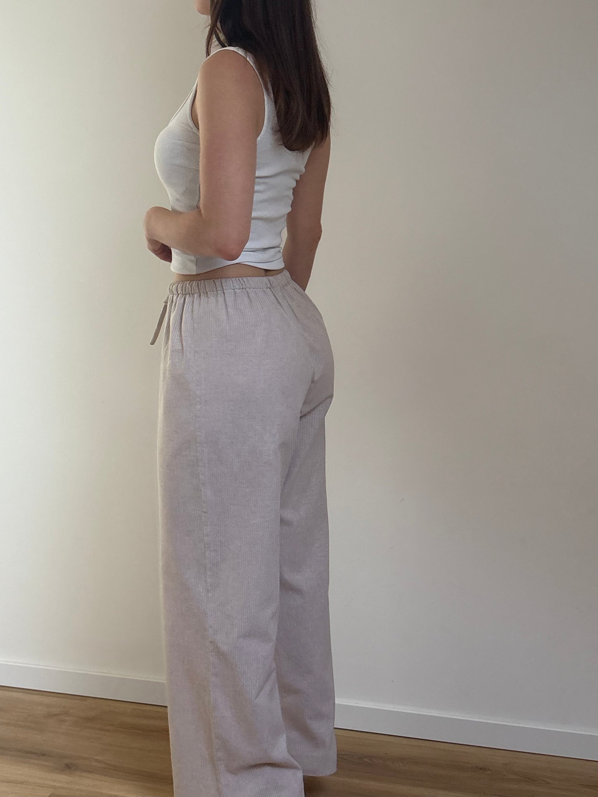 Pantalon de pyjama femme beige en matières 100 % naturelles, coupe large à fines rayures, pyjama confortable et élégant pour l'été.