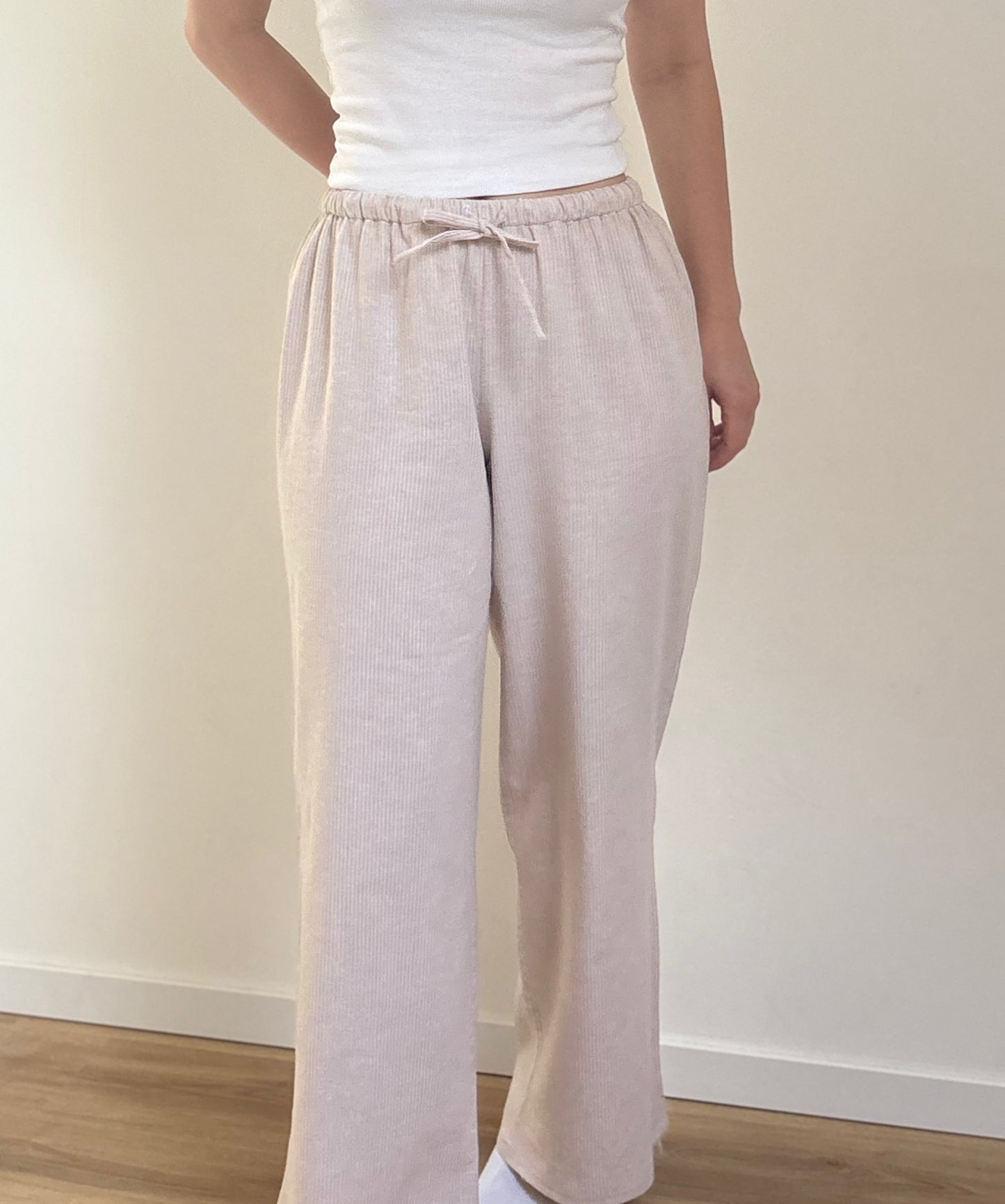 Pantalon de pyjama femme beige en matières 100 % naturelles, coupe large à fines rayures, pyjama confortable et élégant pour l'été.