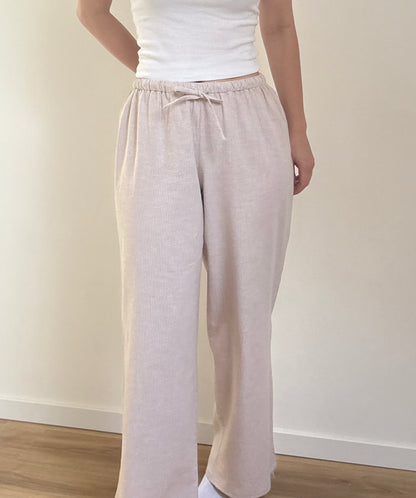 Pantalon de pyjama femme beige en matières 100 % naturelles, coupe large à fines rayures, pyjama confortable et élégant pour l'été.