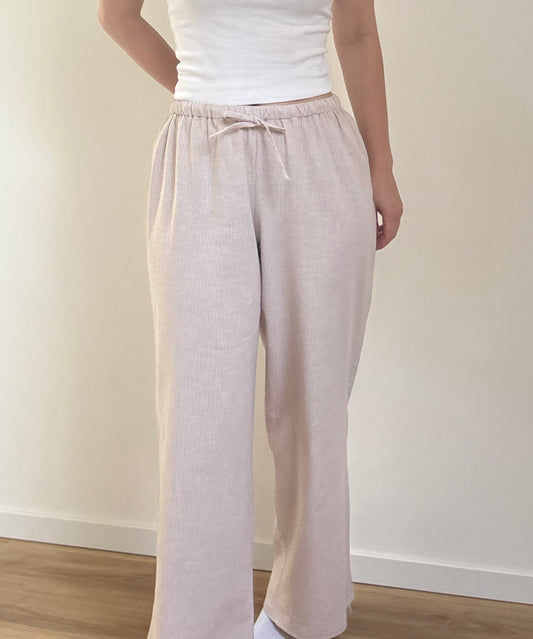 Pantalon de pyjama femme beige en matières 100 % naturelles, coupe large à fines rayures, pyjama confortable et élégant pour l'été.